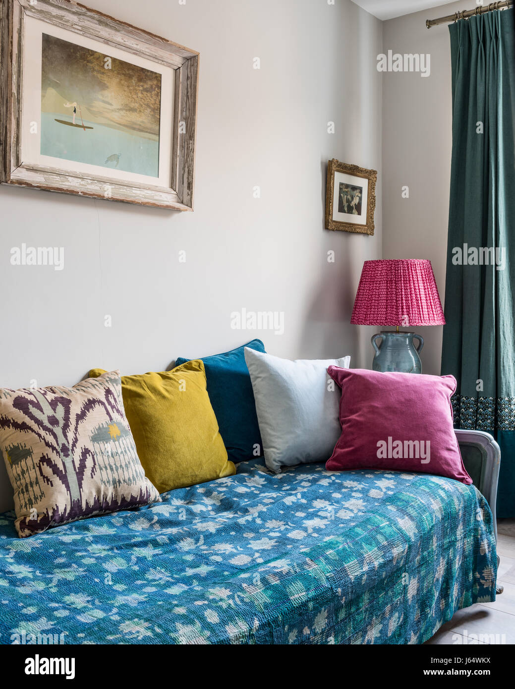 Gesteppte Kantha werfen auf Liege mit einem Sortiment von bunten samt und Ikat Kissen Stockfoto