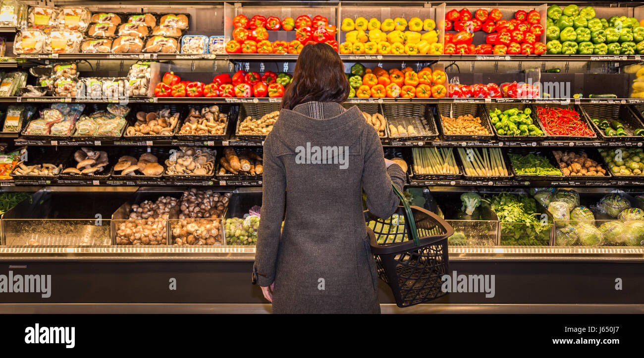 Junge Frau steht vor dem Abschnitt produzieren von einem Lebensmittelgeschäft. Stockfoto