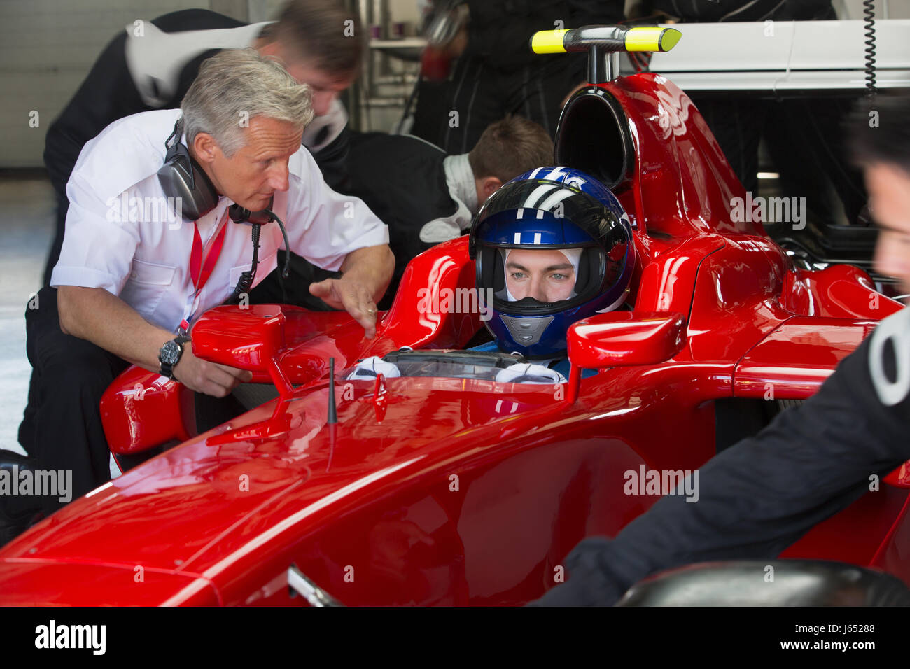 Manager im Gespräch mit Formel 1 Rennfahrer in Werkstatt Stockfoto