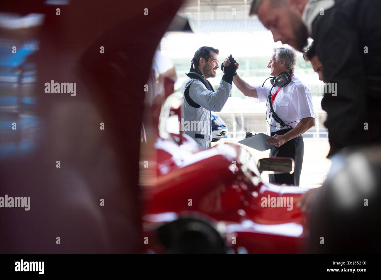 Manager und Formel-1-Rennfahrer high-fiving in Werkstatt Stockfoto