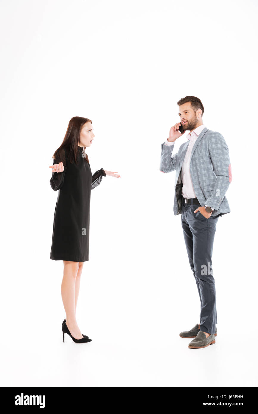 Böse Frau Mann sprechen per Telefon über weißen Hintergrund isoliert betrachten. Auf der Suche zur Seite. Stockfoto