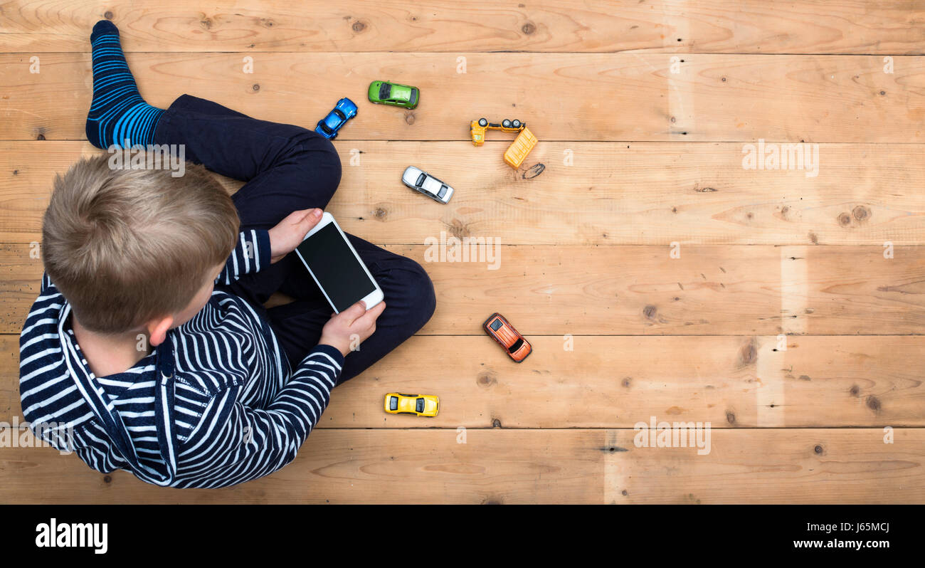 Kleiner Junge spielt mit Smartphone statt Spielzeug Stockfoto