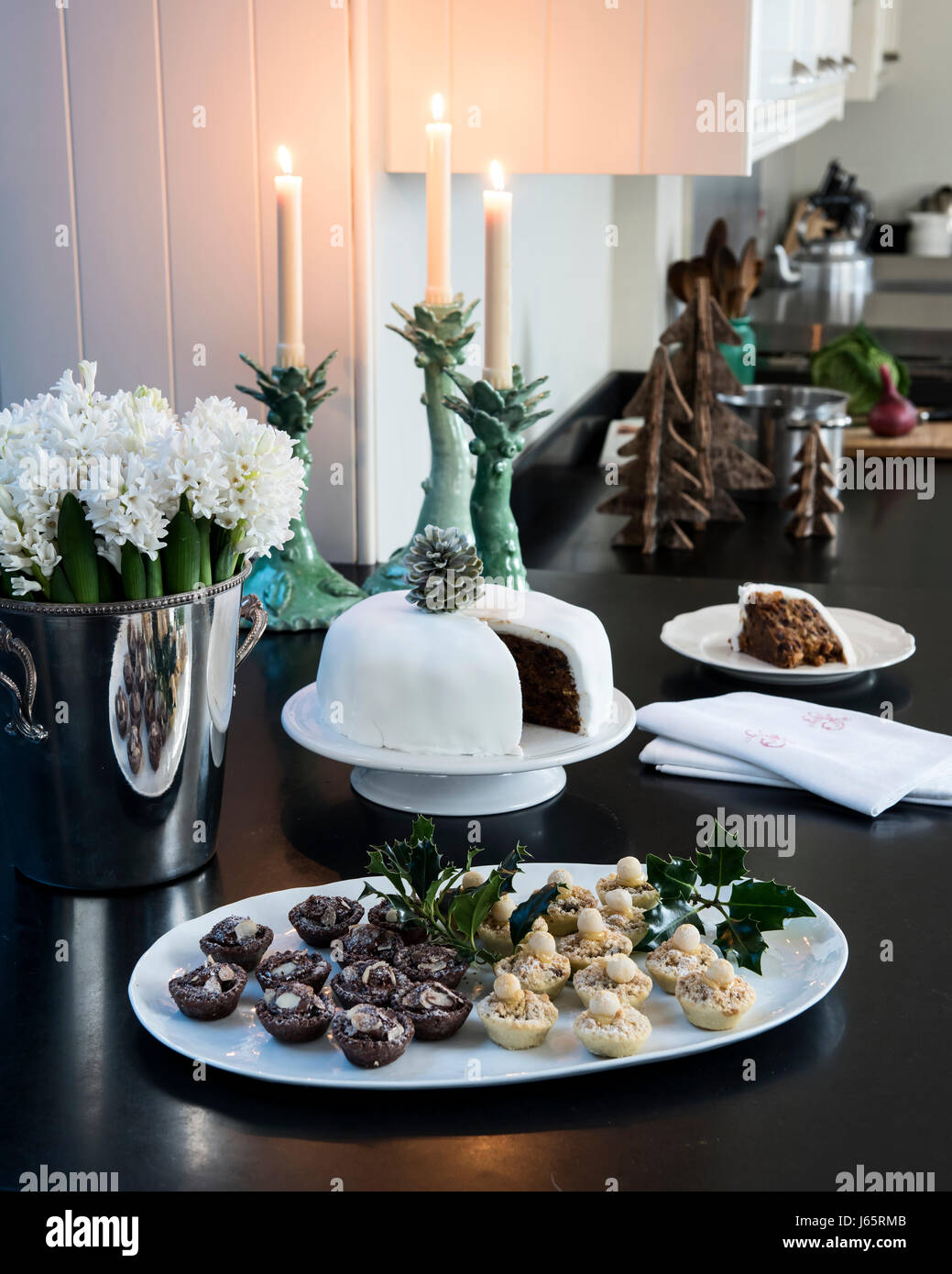 Kleine Törtchen und Weihnachtskuchen auf einem schwarzen Stein Arbeitsplatte in eleganten Candle-light-Küche Stockfoto