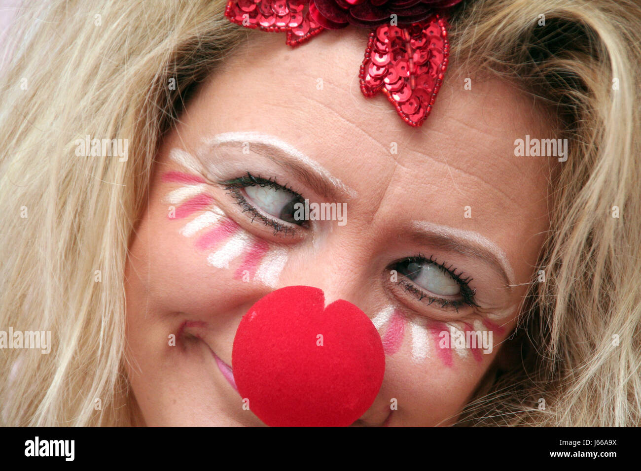 kostümierte Frau mit roter Nase Stockfoto
