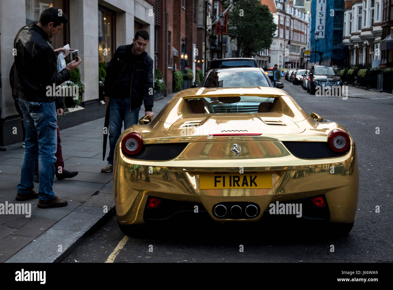 Passanten bewundern eine Gold Ferrari 458 Spider im Besitz von Kickbox-Weltmeister Riad Al-Azzawi, wie es vor Kaufhaus Harrods in Knightsbridge, London geparkt ist. Stockfoto