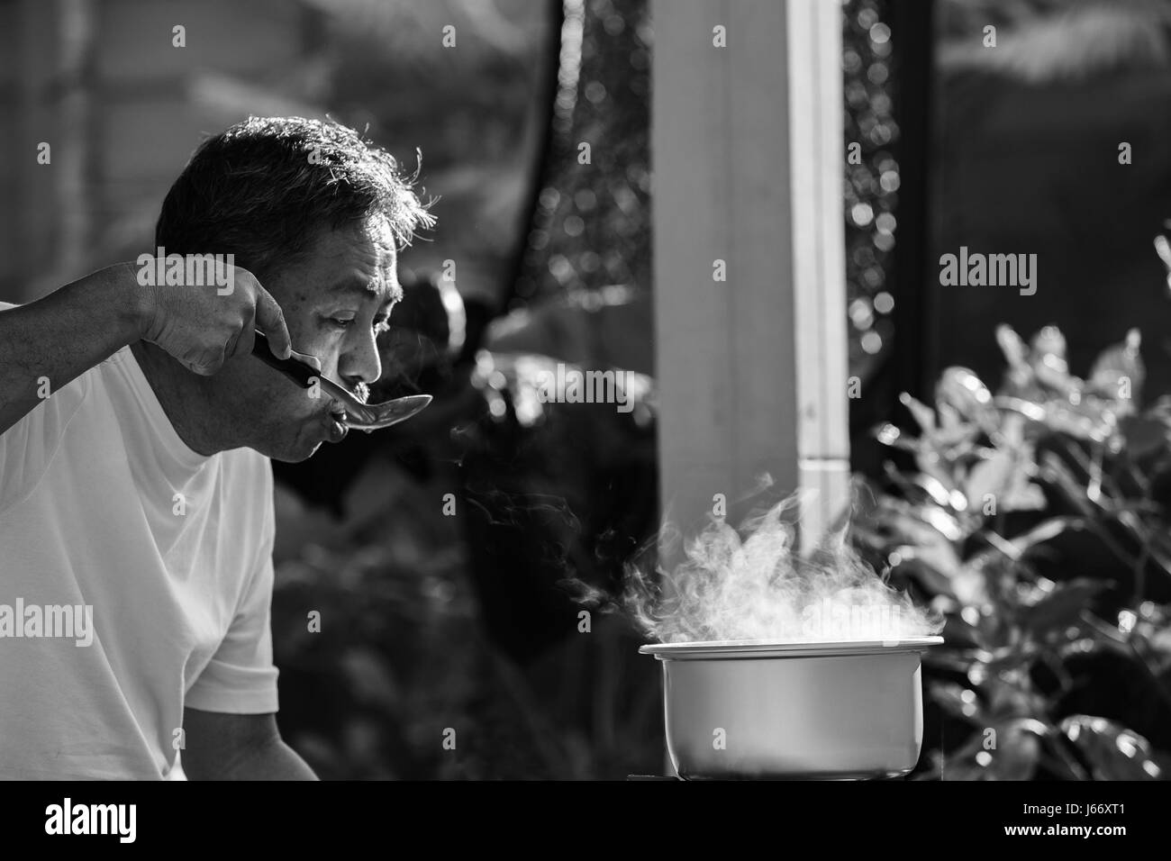 Alter Mann Kochen Essen Morgenmahlzeit im Hot Pot auf lpg-Gas-Herd Stockfoto