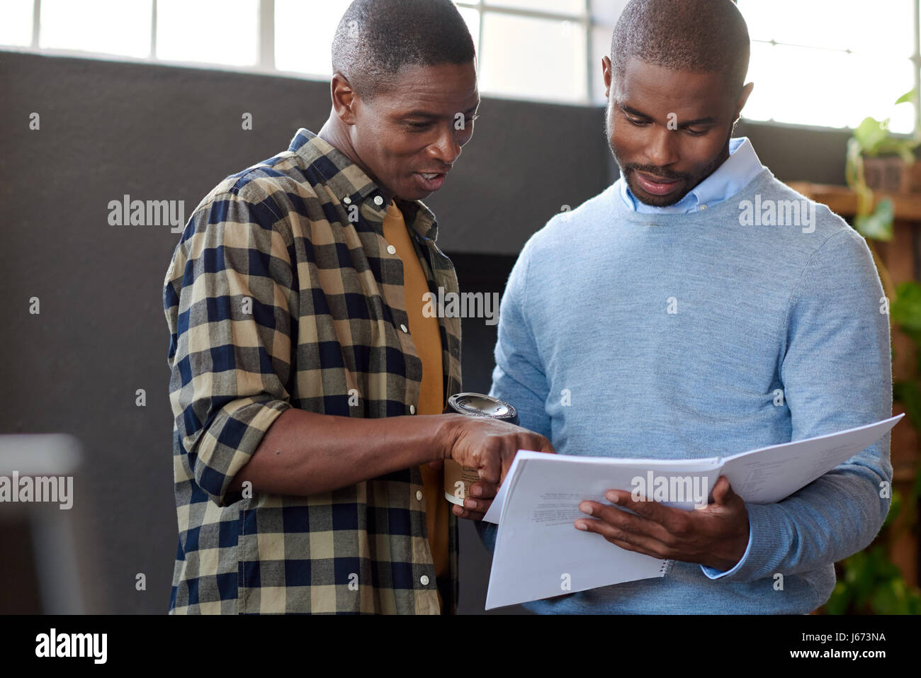 Lächelnde afrikanische Unternehmer diskutieren Papierkram zusammen in einem Büro Stockfoto