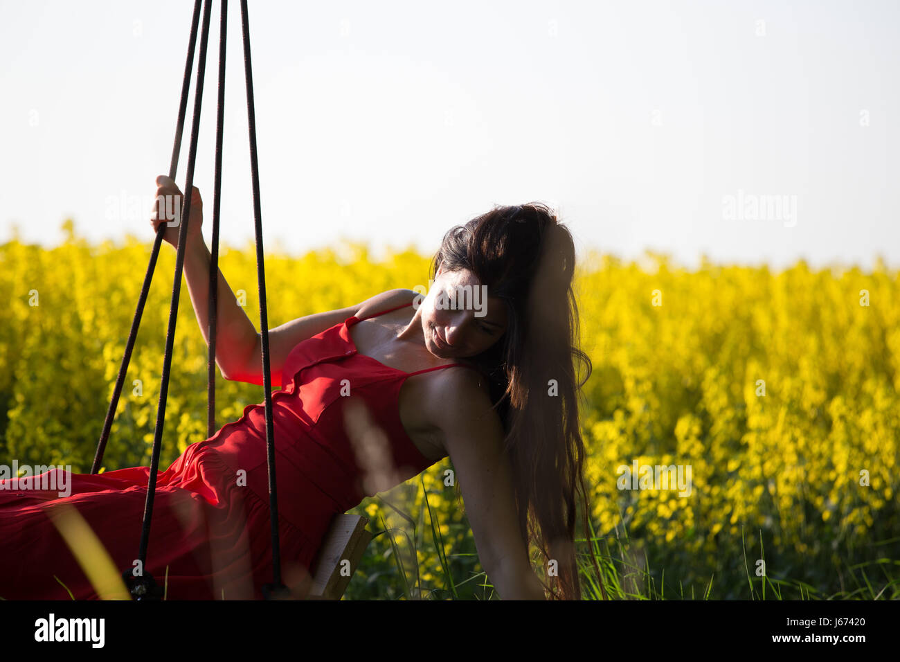 Sommerszene mit Frau auf einer Schaukel Stockfoto