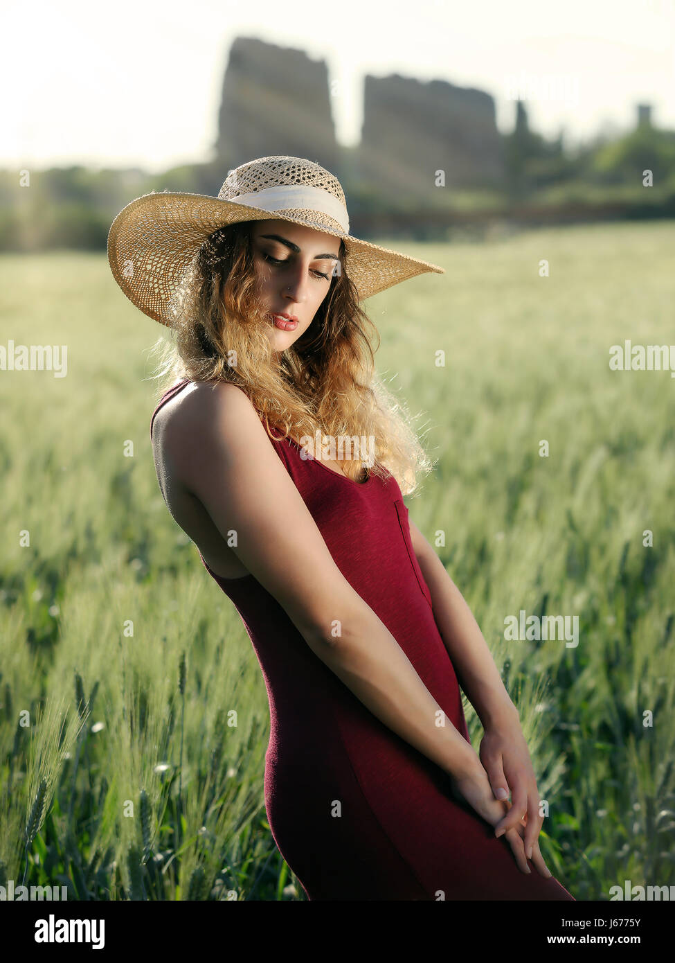 Blonde Mädchen im Freien. Mit Hut und roten Kleid im Weizenfeld. Hintergrundbeleuchtung. Stockfoto