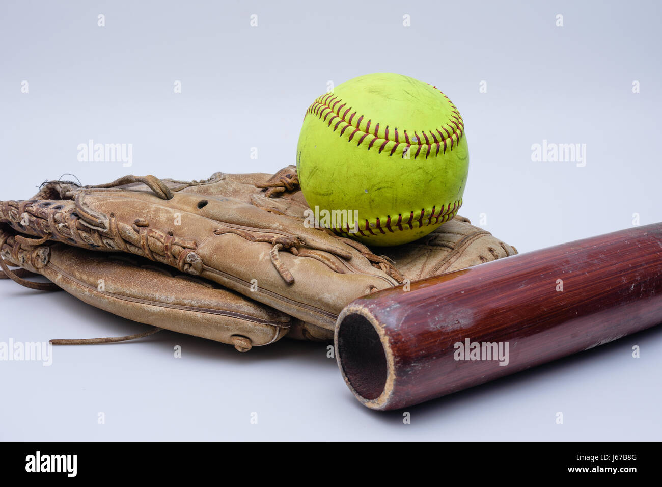 Softball sitzt auf alten Handschuh mit Fledermaus Stockfoto