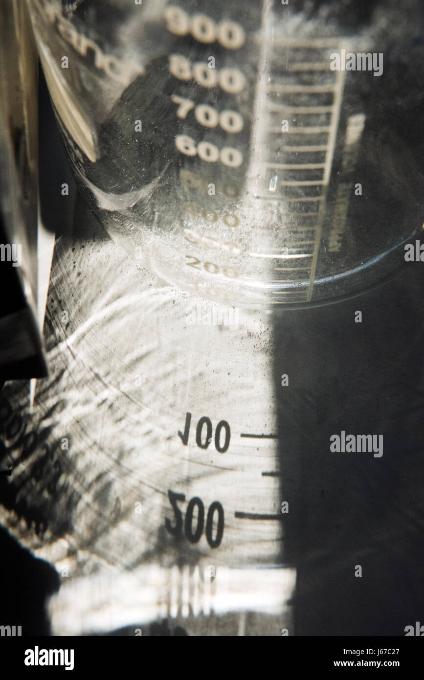 Nahaufnahme von Laborglasbechern mit Messmarkierungen, die Lichtreflexionen und abstrakte wissenschaftliche Details zeigen Stockfoto