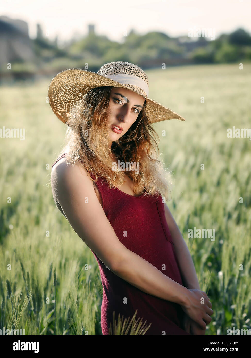 Blonde Mädchen im Freien. Mit Hut und roten Kleid im Weizenfeld. Hintergrundbeleuchtung. Stockfoto