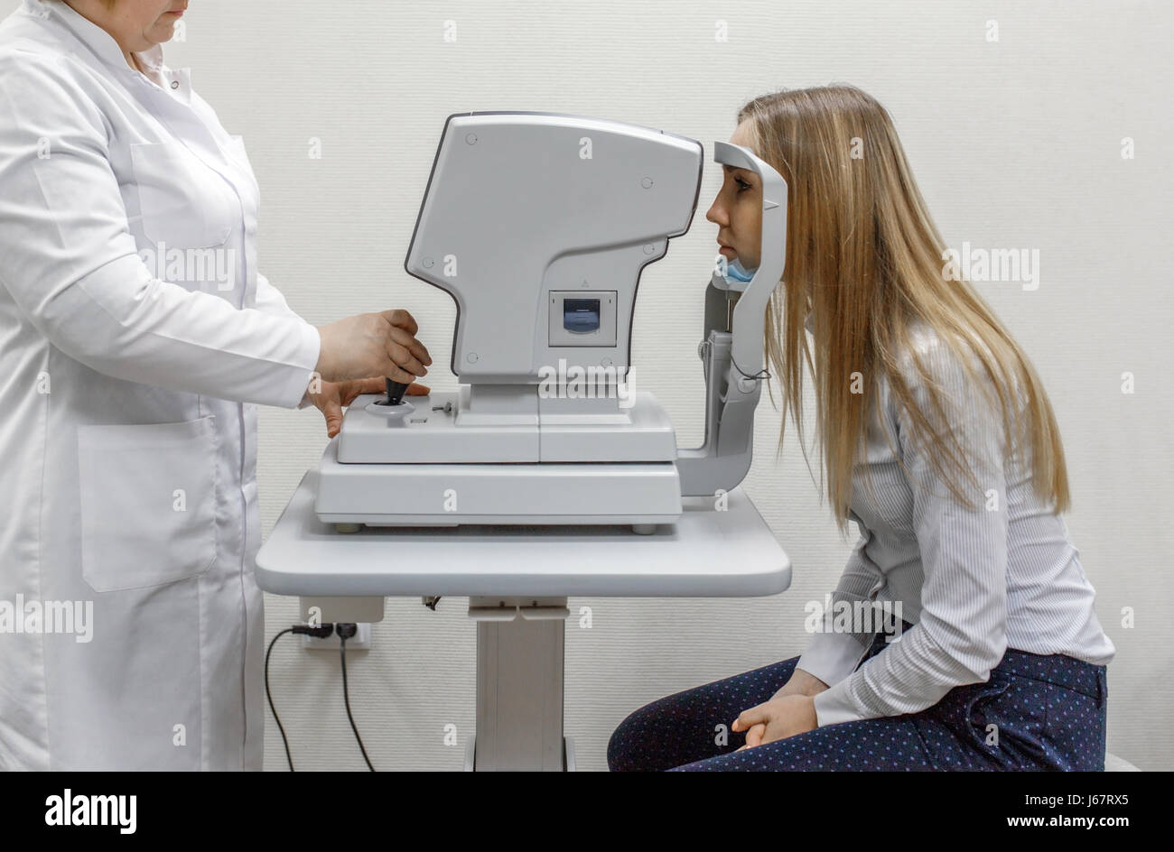Aufmerksame Augenarzt Untersuchung Patientin auf Spaltlampe in Augenklinik Stockfoto