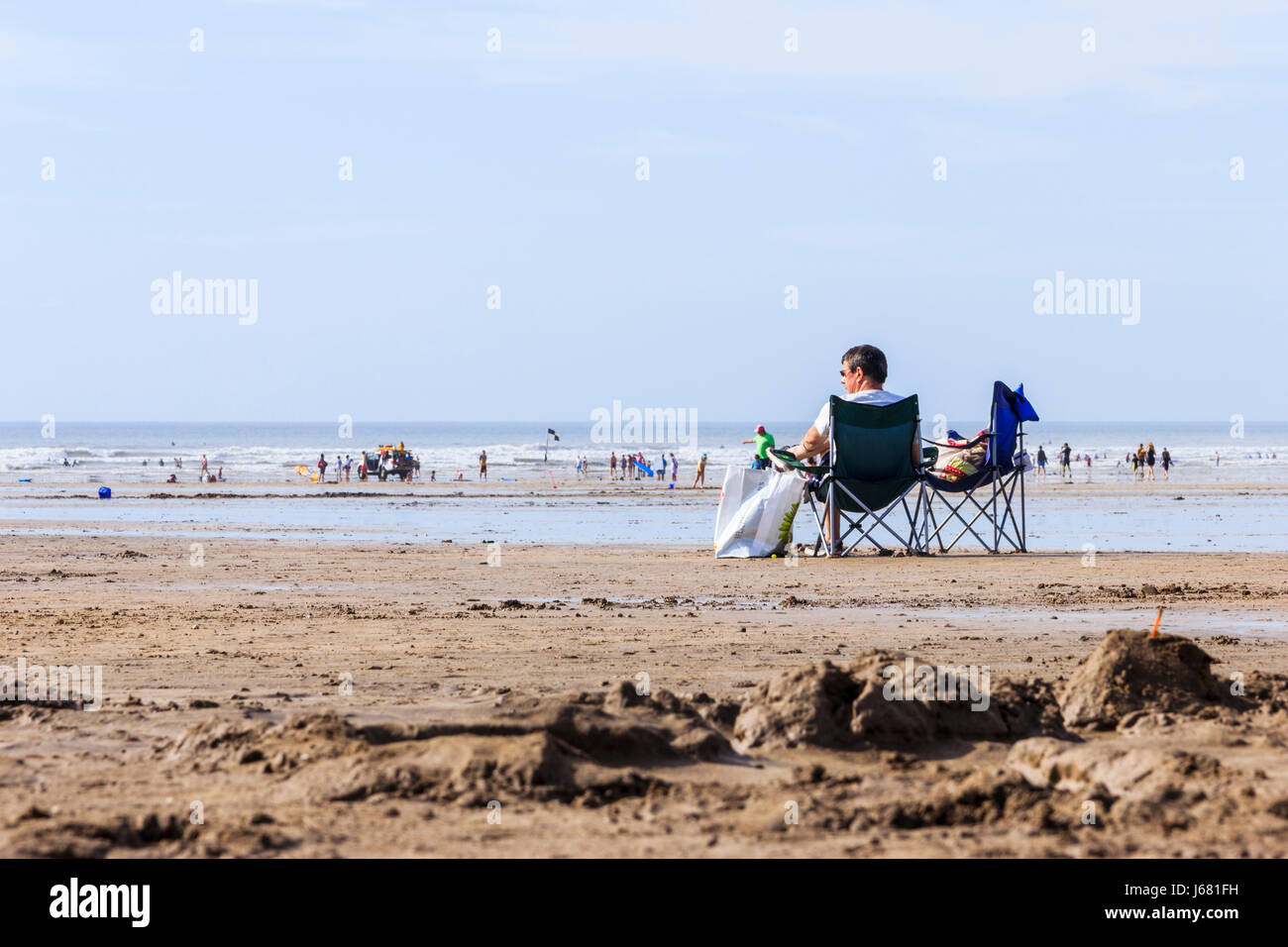 Ein Mann in einer klappbaren Liegestuhl sitzend Blick aus Meer bei Westward Ho!, Devon, Großbritannien Stockfoto