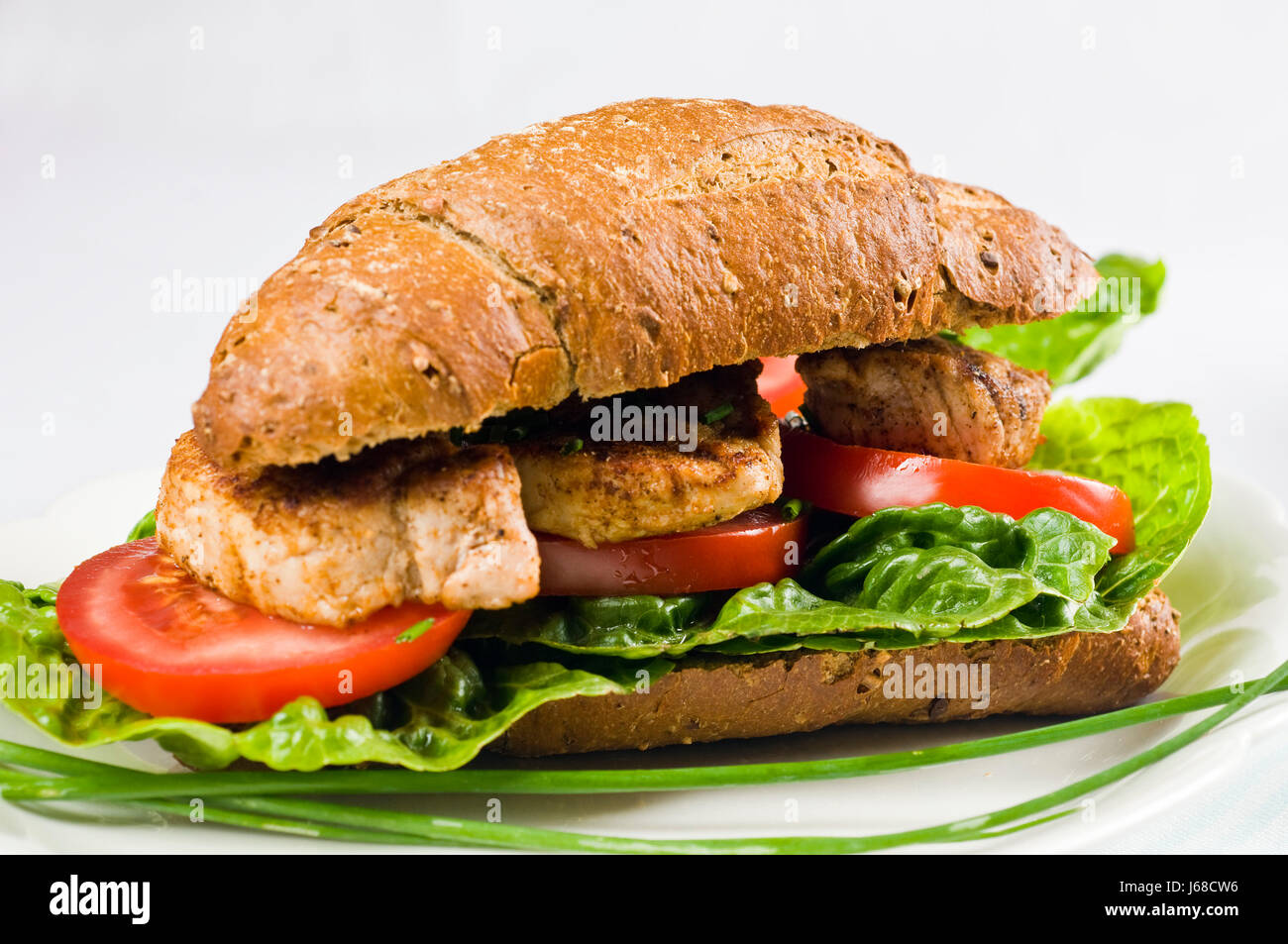 Belegtes Vollkorn Brötchen mit Schweinefleisch, Salat, Tomaten und Paprika Stockfoto