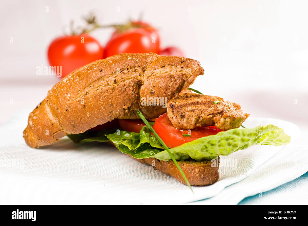 Belegtes Vollkorn Brötchen mit Schweinefleisch, Salat, Tomaten und Paprika Stockfoto