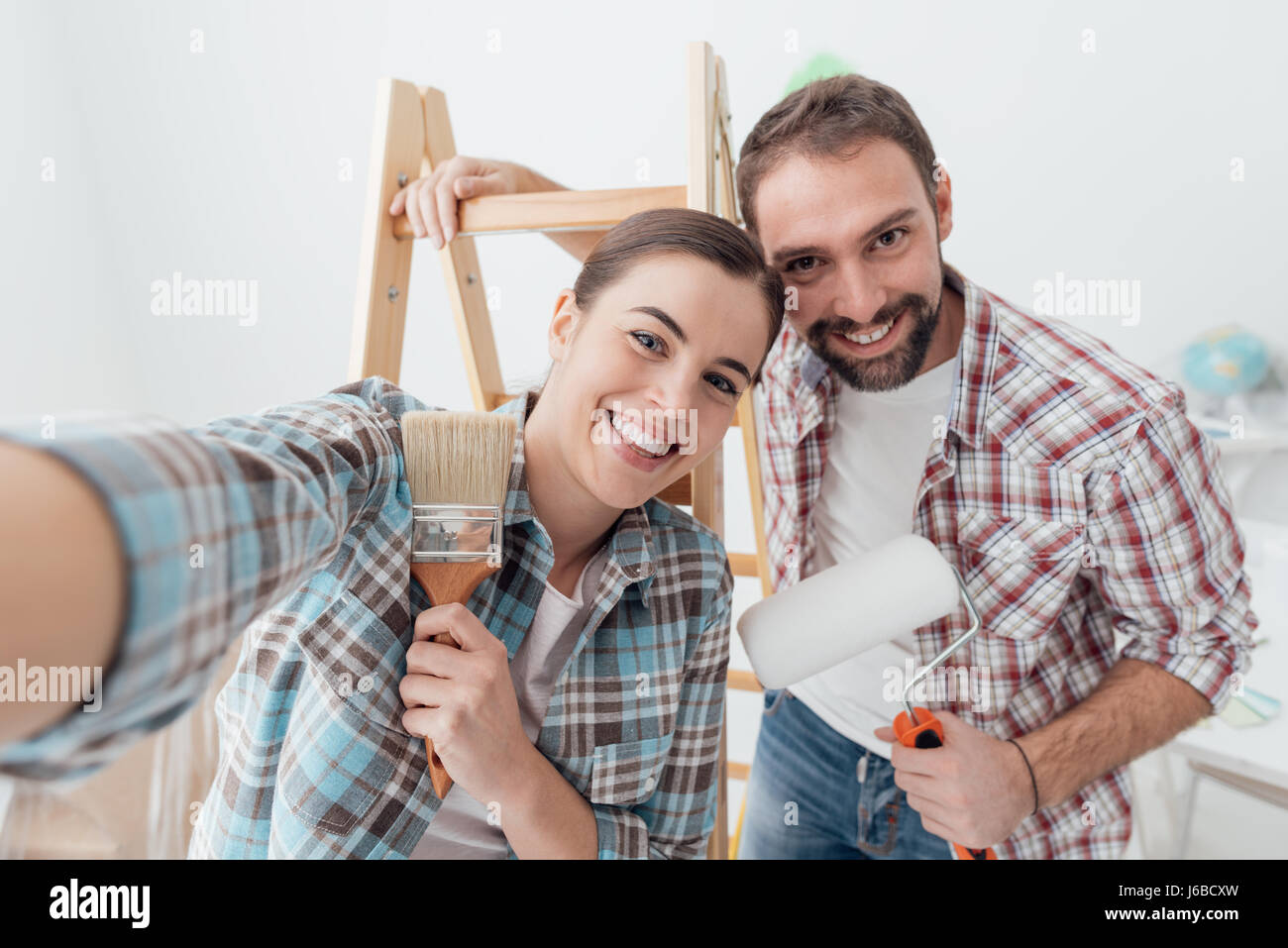 Kreative junge Paar renovieren ihr Haus und Malerei Wände, sie nehmen ein Selbstporträt zusammen und lächelt in die Kamera Stockfoto