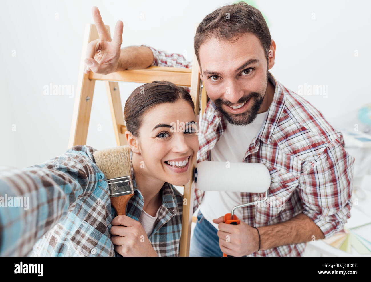 Kreative junge Paar renovieren ihr Haus und Malerei Wände, sie nehmen ein Selbstporträt zusammen und lächelt in die Kamera Stockfoto