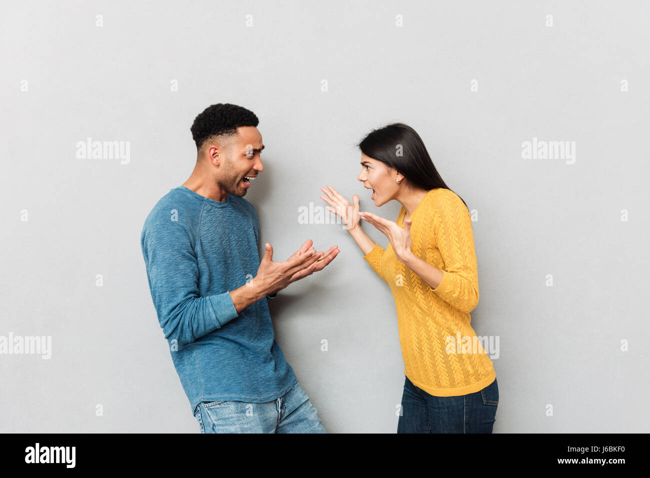 Junge Paare, die einen Streit haben. Afrikaner und böse Frau schelten einander isoliert Stockfoto