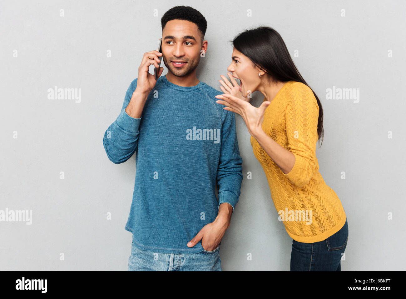 Böse Frau schrie ihr Mann während er telefonieren isoliert Stockfoto