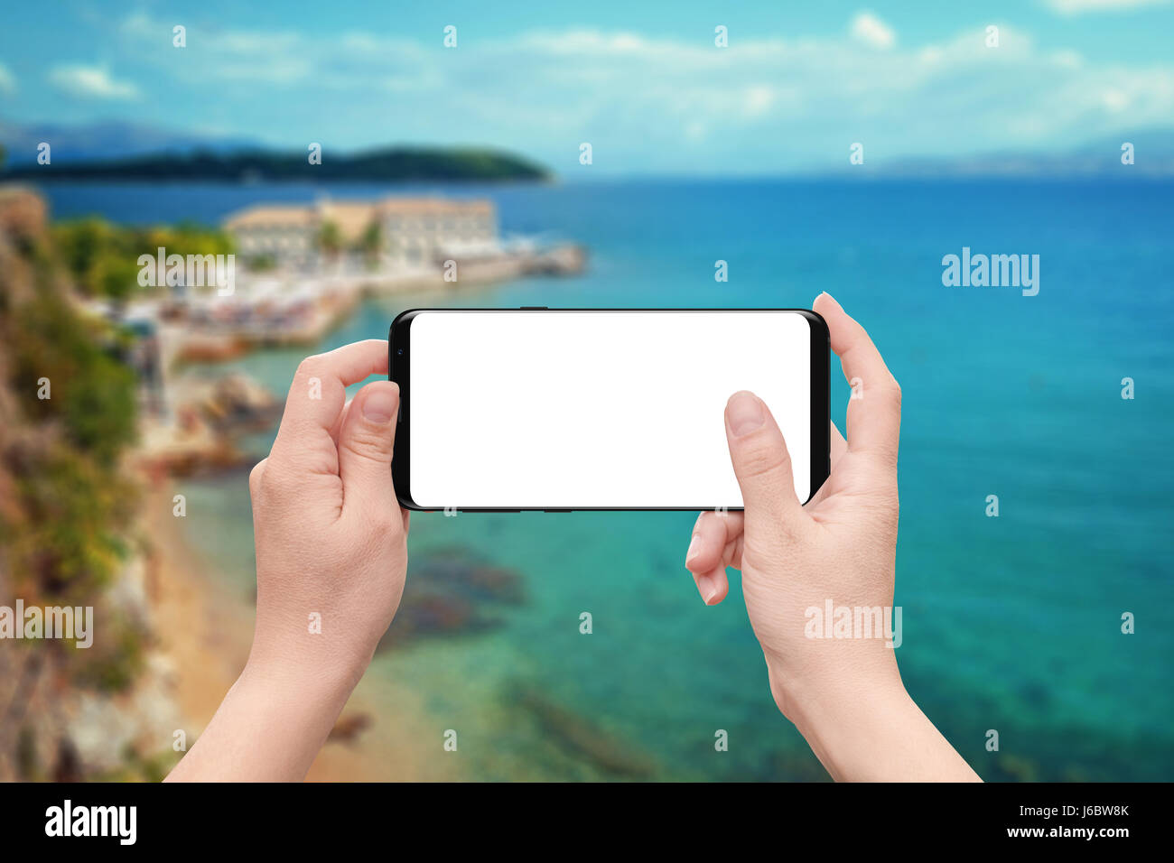 Frau zum Spiel oder app auf dem Handy mit isolierten weißen Bildschirm verwenden. Küste und Meer im Hintergrund. Stockfoto