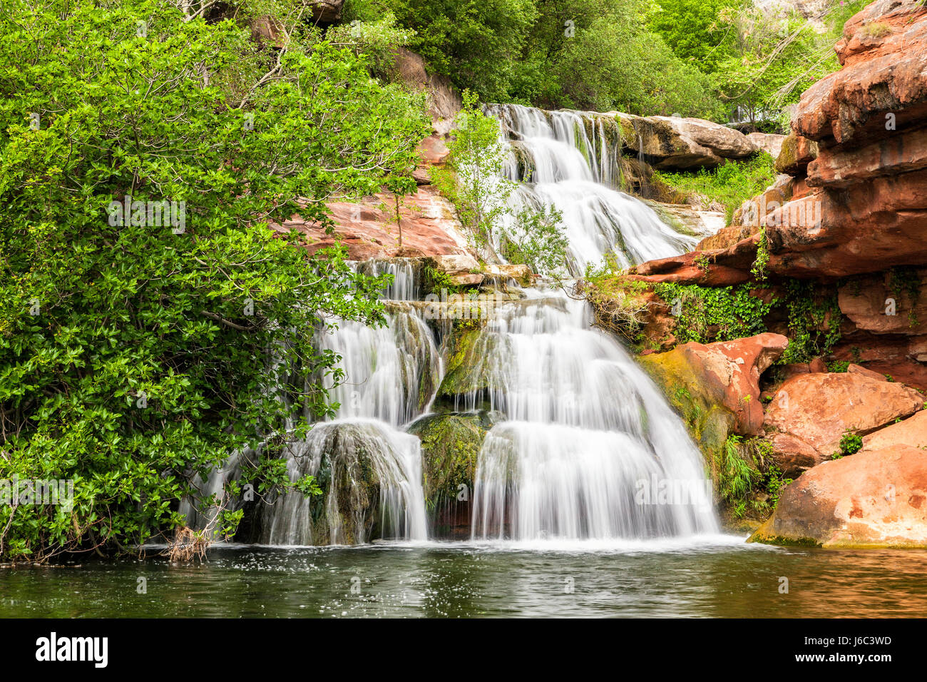 Wasserfall Kaskaden am roten Felsen unter Espai natürliche Sant Miquel del Fai Kloster in Katalonien, Spanien. Stockfoto