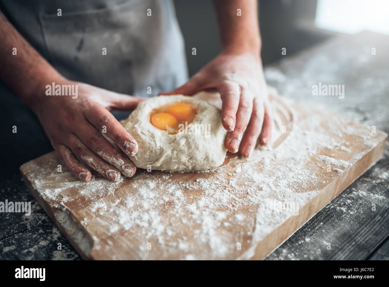 Männliche Bäcker Händen vermischen den Teig mit Ei. Brot-Vorbereitung. Hausgemachte Backwaren Stockfoto