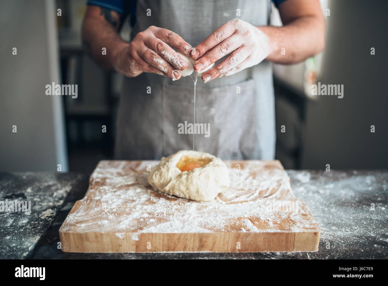 Koch Händen vermischen den Teig mit Ei. Brot-Vorbereitung. Hausgemachte Backwaren Stockfoto