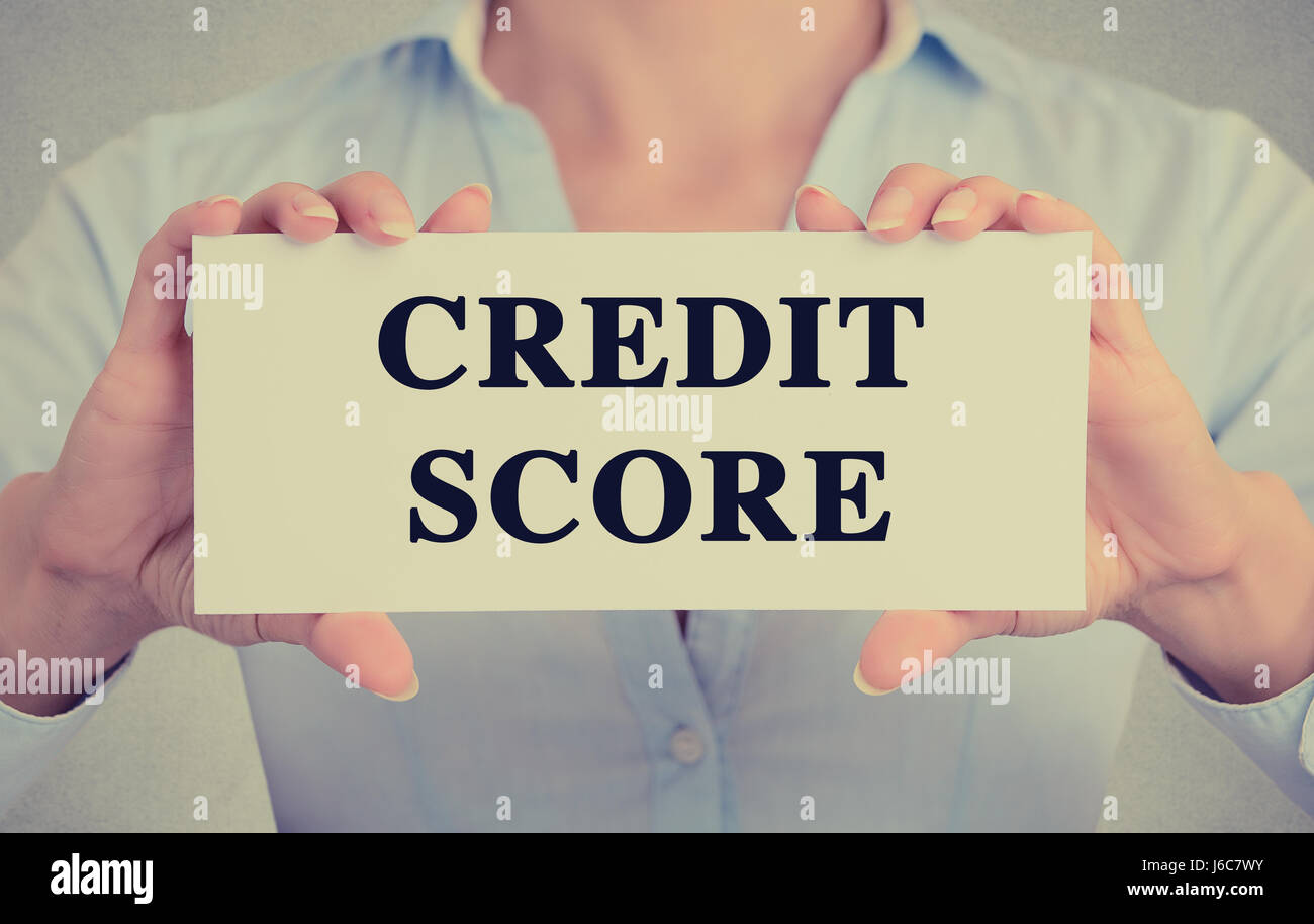 Closeup Geschäftsfrau Hände halten weiße Karte Zeichen mit Credit Score Textnachricht auf graue Wand Büro Hintergrund isoliert. Retro-Instagram Stil imag Stockfoto