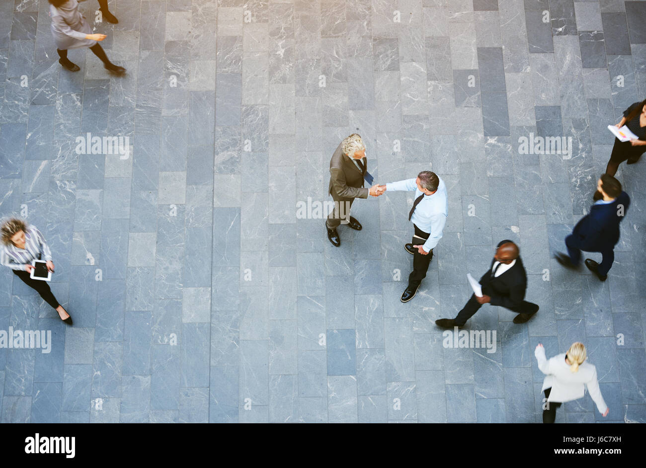 Von oben zwei Erwachsenen Geschäftsleute traf Händeschütteln im Büro Halle mit Arbeiter herumlaufen. Stockfoto