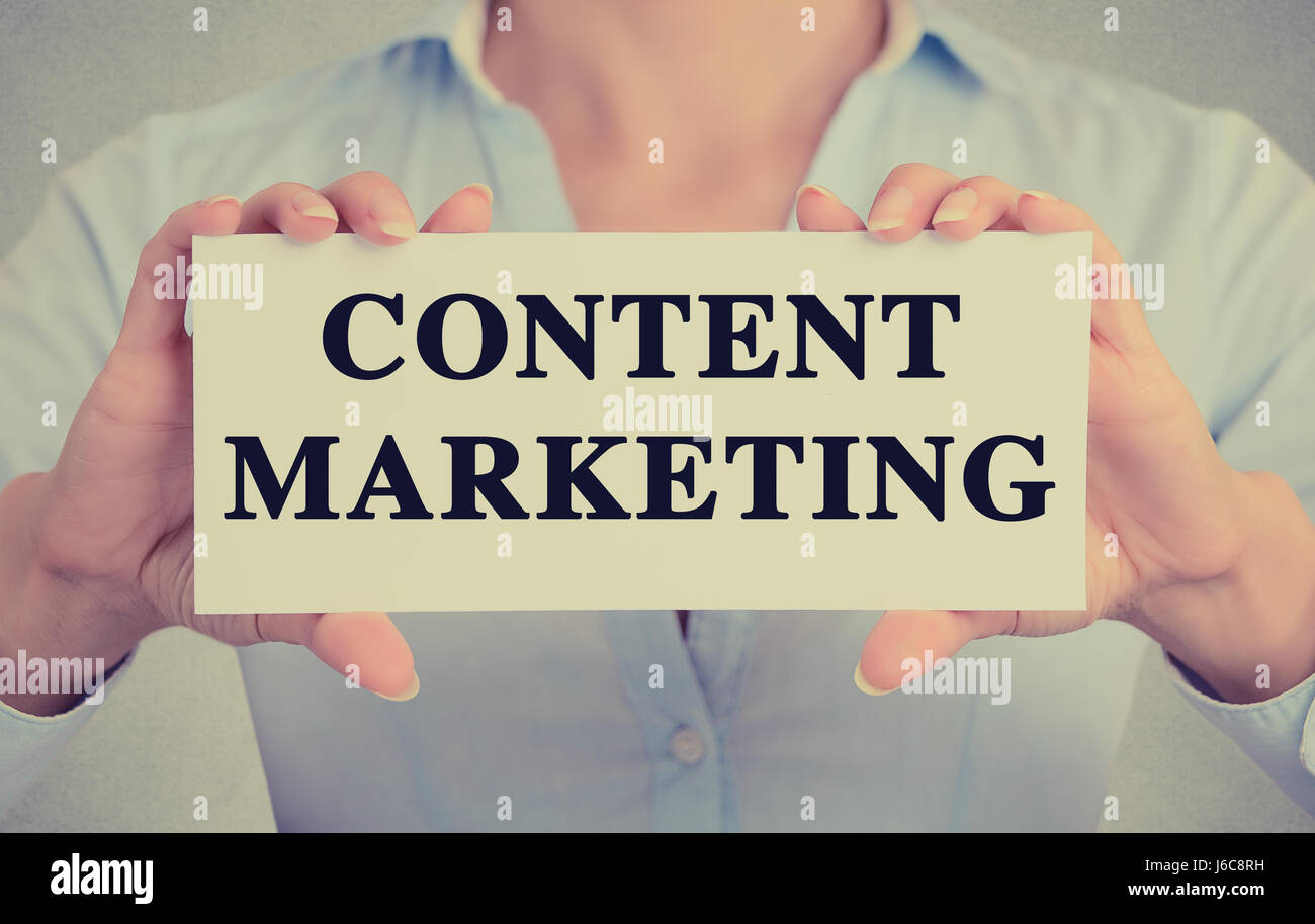 Closeup Geschäftsfrau Hände halten weiße Karte Zeichen mit Content marketing SMS auf graue Wand Büro Hintergrund isoliert. Retro-Instagram-Stil Stockfoto