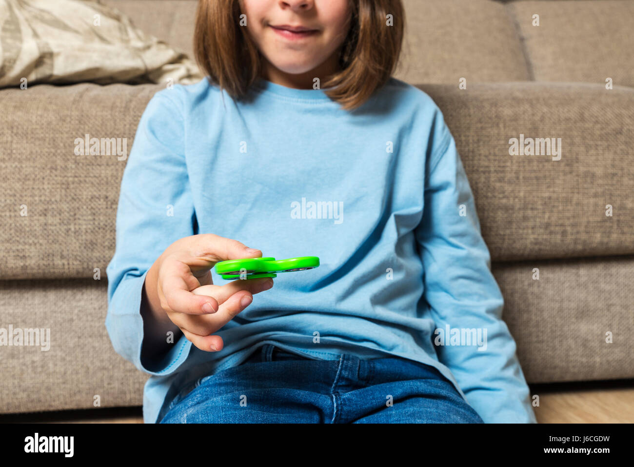 Kleines Mädchen mit grünen Fidget Spinner Spielzeug spielen, um Stress zu Hause Stockfoto