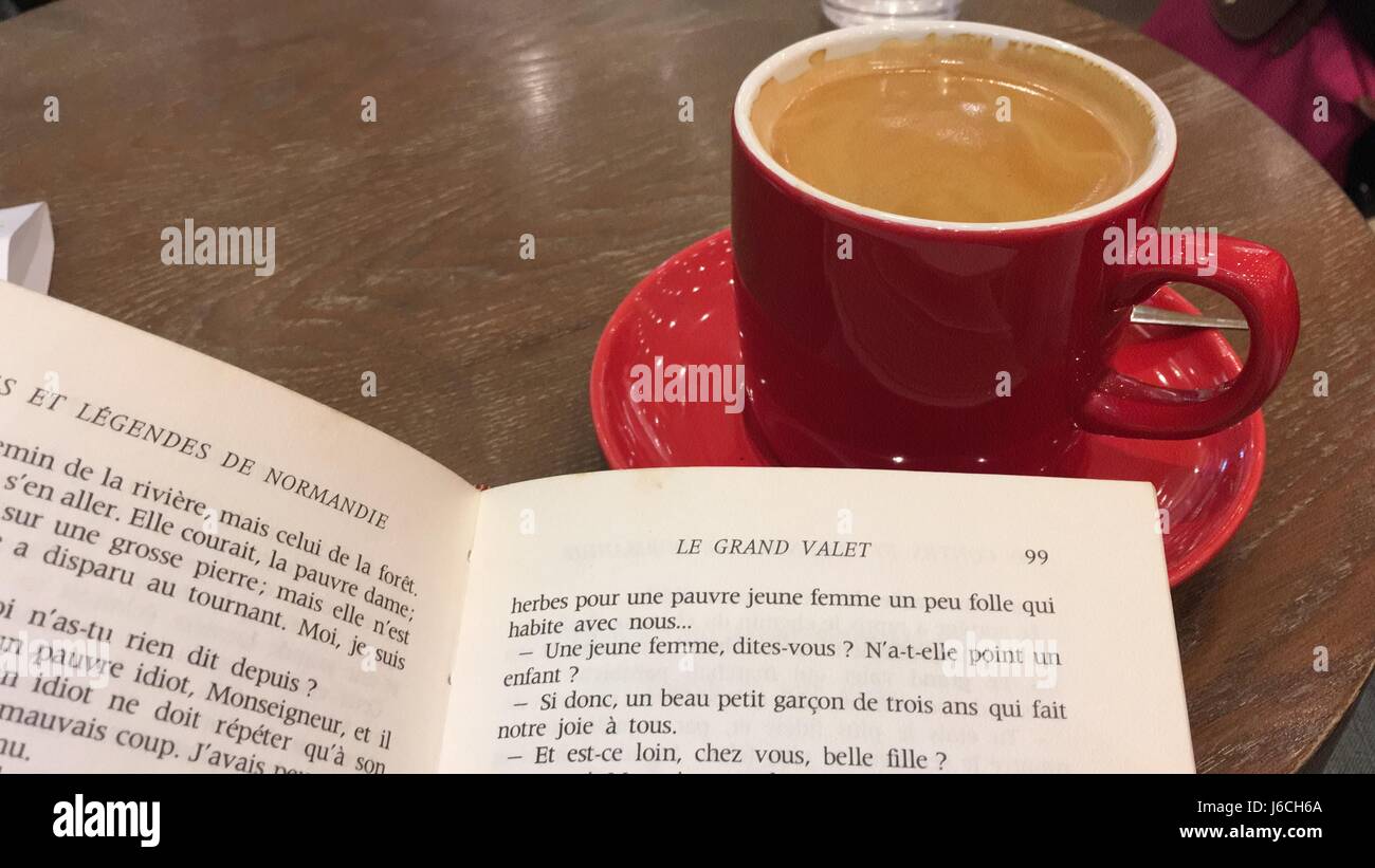 Rote Tasse Kaffee in einem Café und einen Roman oder ein Buch zu lesen Stockfoto