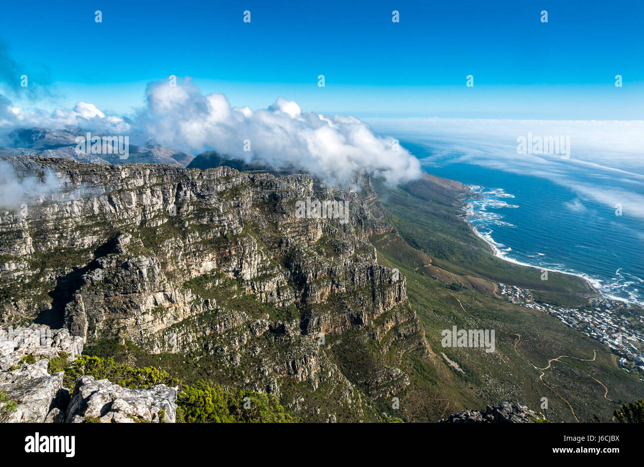 Blick vom Tafelberg, Kapstadt, Südafrika, auf das Meer und die Küstenstraße mit Wolkenformation, die als Tischdecke über zwölf Apostel bekannt ist Stockfoto