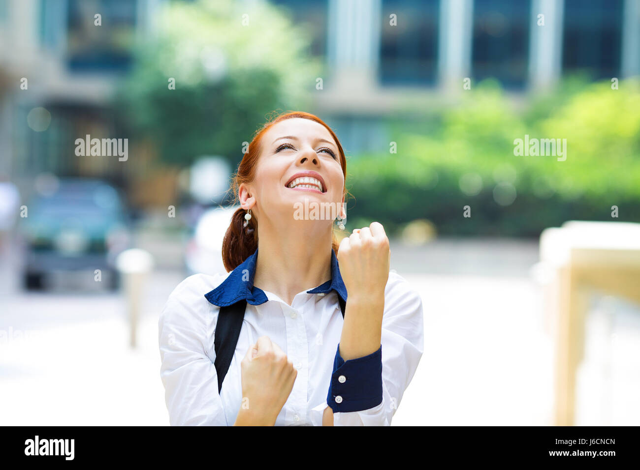 Closeup Portrait glücklich lächelnde Geschäftsfrau mit Arme nach oben, aufgeregt Pumpen Fäuste, feiert isoliert Hintergrund im freien Unternehmenszentrale. Positive Stockfoto