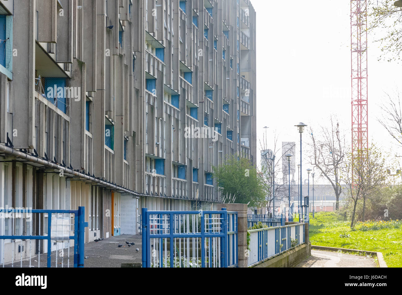 Flache Sozialwohnungen Block, Robin Hood Gardens, in East London mit einem roten Gebäude Kran im Hintergrund Stockfoto