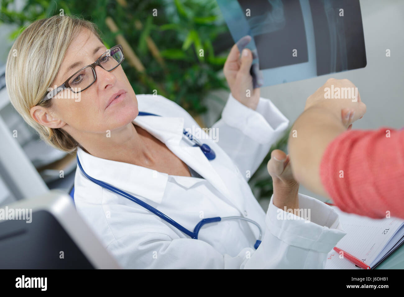 Arzt hält Xray und Blick auf den Arm des Patienten Stockfoto