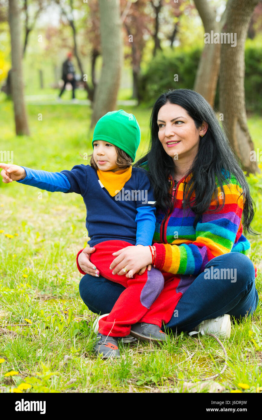 Mutter und Sohn sitzen auf Rasen und der junge zeigt etwas Weg zu seiner Mutter Stockfoto