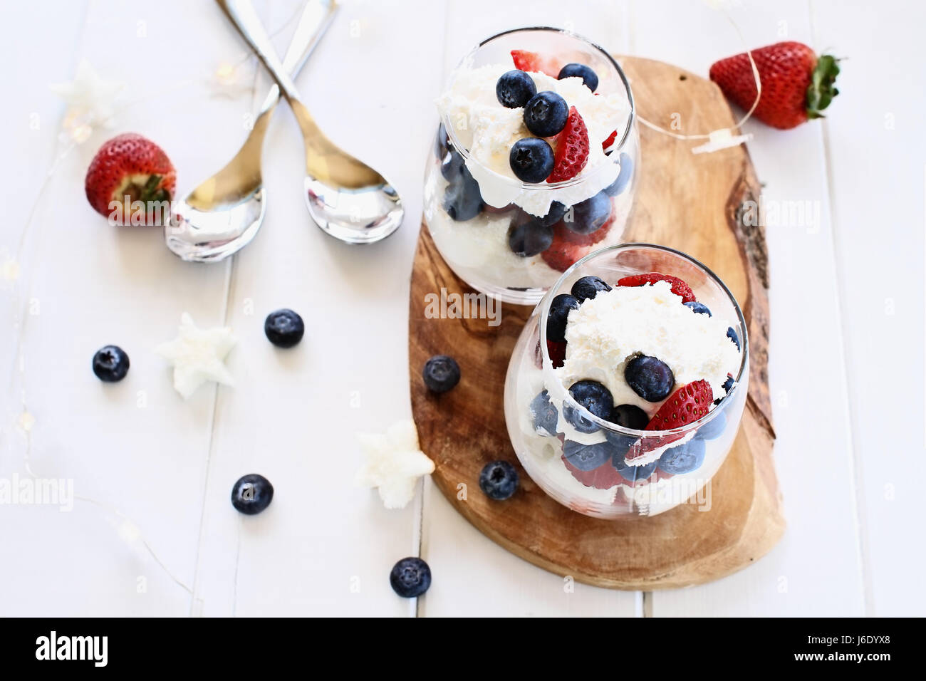 Kleinigkeiten mit Heidelbeeren, Erdbeeren, Schlagsahne und Sterne geformte Sandkuchen weißem Holz Hintergrund gemacht. Perfekt für vierten Juli. Sha Stockfoto