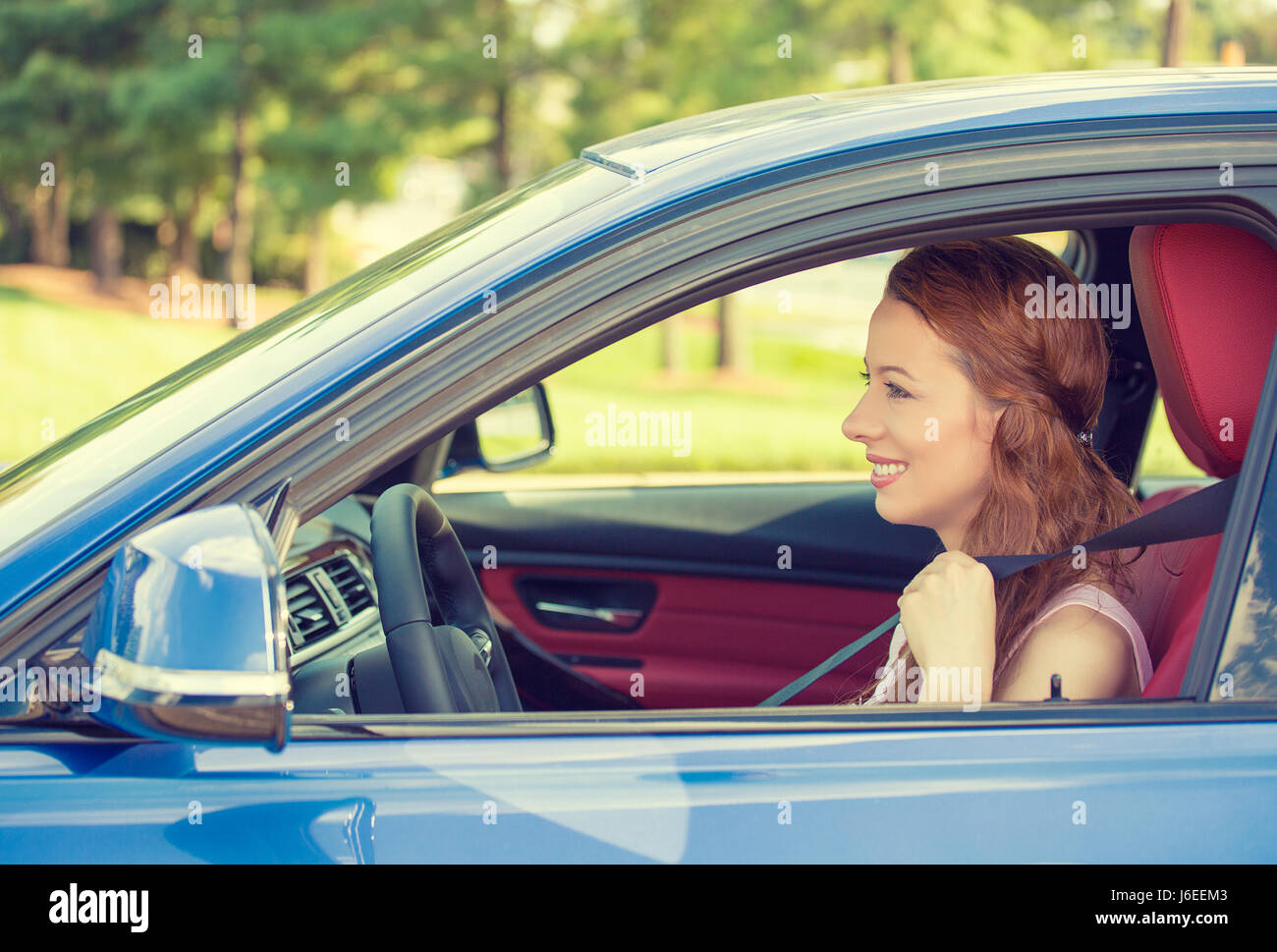 Gerne schöne junge Frau, die ihr neues blaues Auto fahren Stockfoto