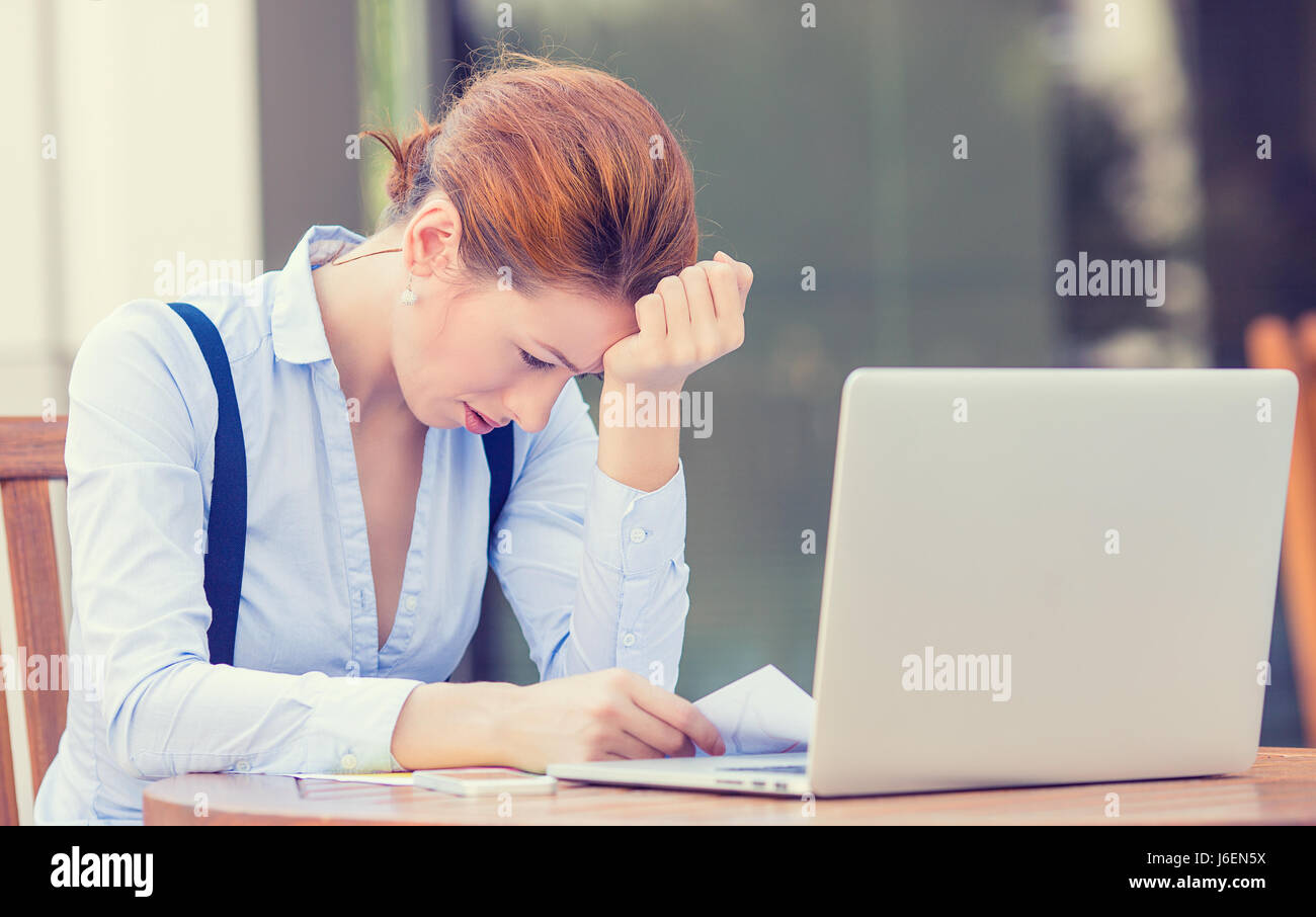 Porträt junger betonte unzufrieden besorgt Business-Frau vor Laptop Computer isoliert im Freien Stadt Gebäude Hintergrund sitzen. Negativen fac Stockfoto