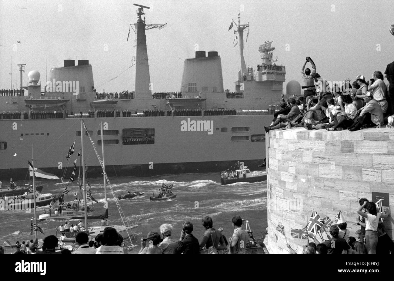 AJAXNETPHOTO. 17. SEPTEMBER 1982. PORTSMOUTH, ENGLAND - UNBESIEGBAR RETOURE - DIE TRÄGER HMS UNBESIEGBAR NACH PORTSMOUTH KEHRT, BEGLEITET VON EINER FLOTTE VON GÖNNERN AM ENDE DES SÜDATLANTIK PFLICHT WÄHREND DES FALKLAND-KAMPAGNE FOTO: SIMON BARNETT/AJAX REF: 820917 33 Stockfoto