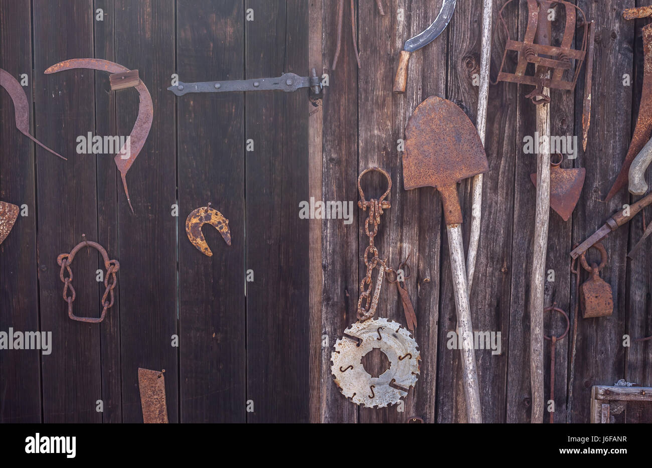 Landw. Geräte hängen braun Holzwand Stockfoto