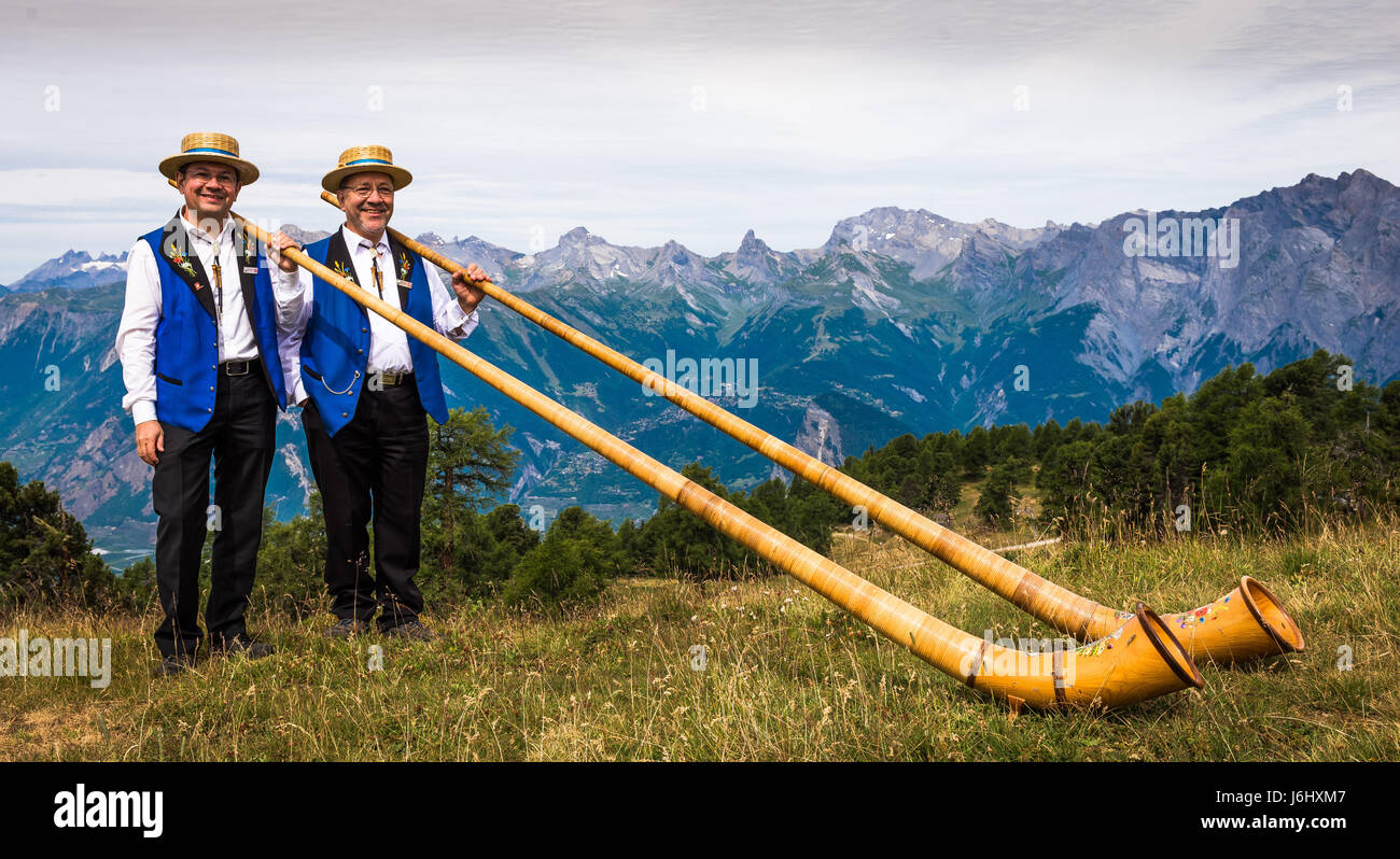 Zwei Alpine Horn-Spieler nehmen am Cor des Alpes Festival in Nendaz, Wallis, Schweiz, Teil Stockfoto