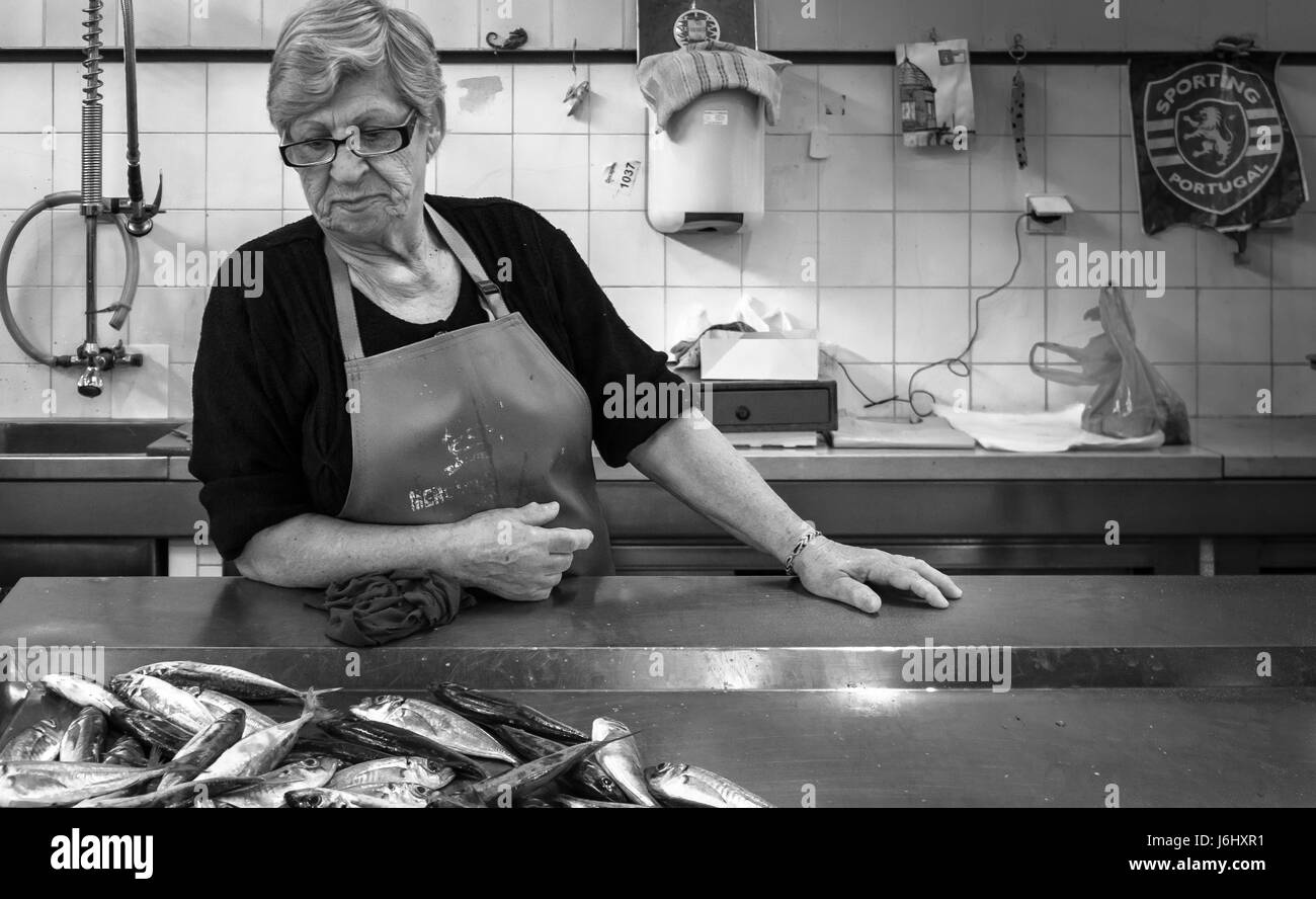 Fischhändler im Laden, der die Fische auf einer Theke in Portugal ansieht Stockfoto