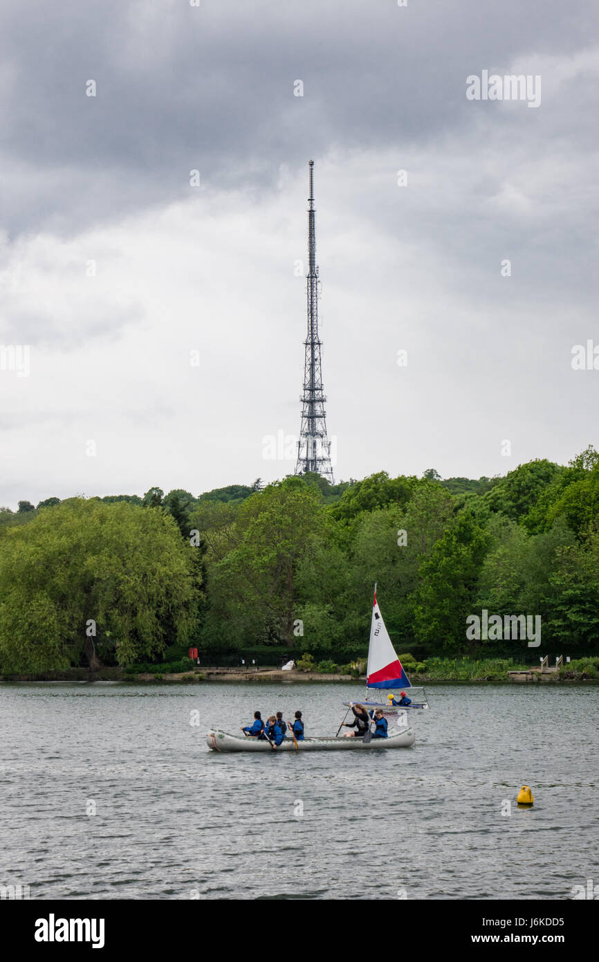 Menschen sehen Sie Segeln auf South Norwood See an einem Frühlingstag zu üben, während die Übertragung von Crystal Palace Station in der Zeitmessung gesehen werden kann Stockfoto