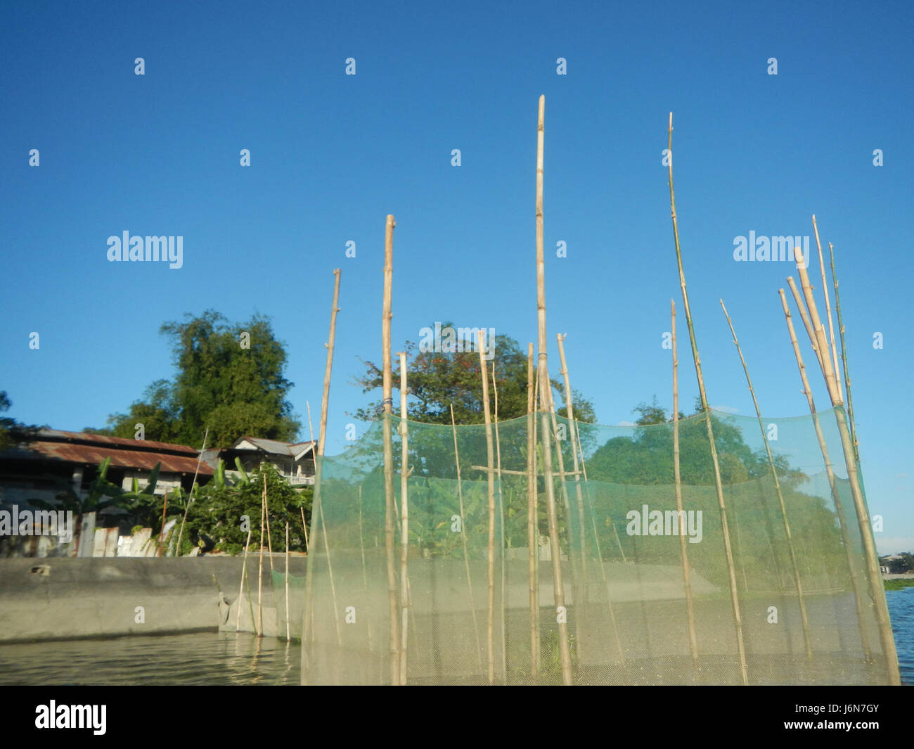 Dieses Bild zeigt die Riprap-Konstruktion entlang des Flusses in Pulilan, Plaridel, Bulacan, mit Bäumen, die das Gebiet säumen. Die Riprap dient als Schutzmaßnahme gegen Erosion entlang des Flusses. Stockfoto