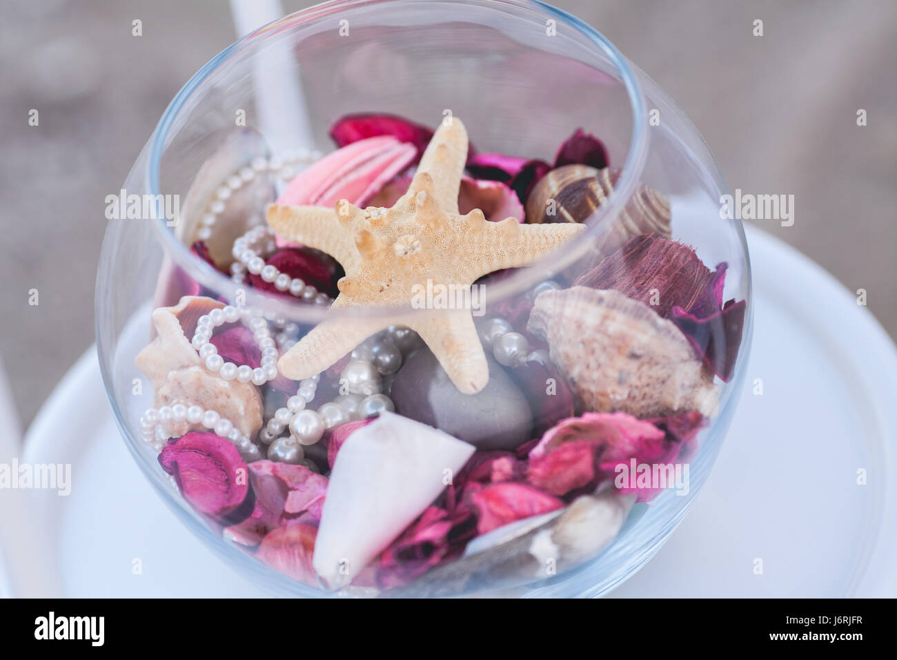 leicht verschmutzte Sterne, dafГјr Perlen liegen transparent für eine Glasvase mit violett und rosa Blüten. Stockfoto