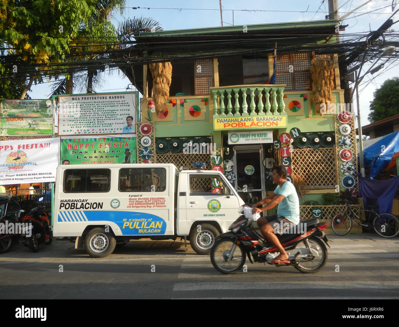Dieses Bild zeigt die Pulilan Central School auf den Philippinen mit bemerkenswerten Sehenswürdigkeiten wie der Champagne Palm und dem nahe gelegenen Fluss, die lokale Besonderheiten der Gemeinde hervorheben. Stockfoto