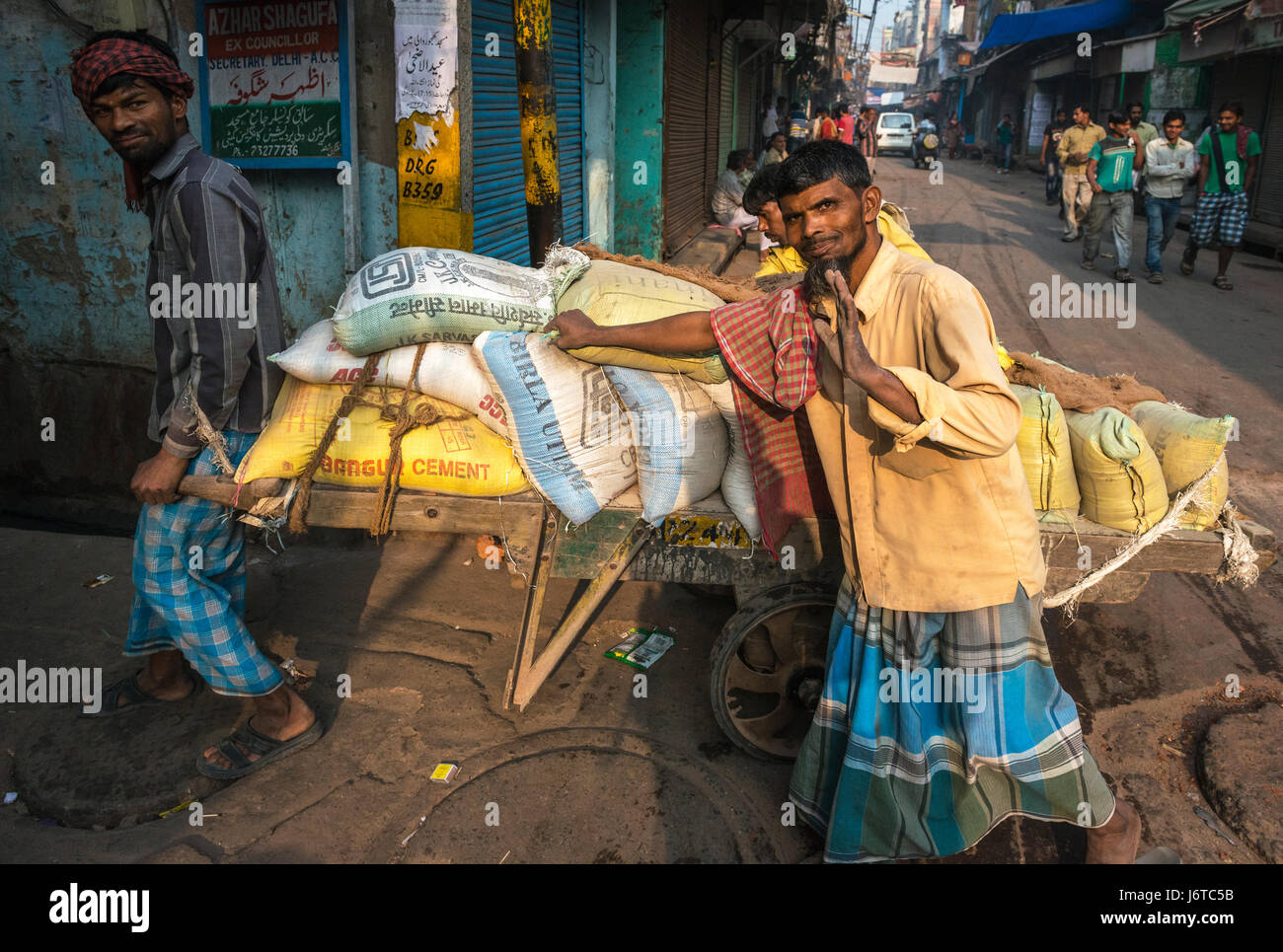 Delhi, Indien - 10. November 2012 - drei Männer schieben einen Wagen mit Constuction Material, ist zur Veranschaulichung, dass Handarbeit noch eine dominierende Form der Arbeit Stockfoto